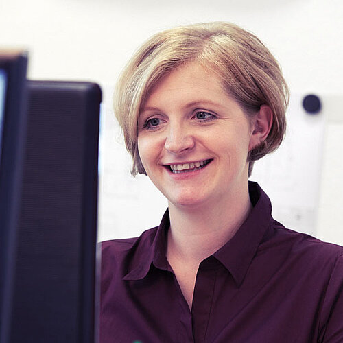 Eine blonde Frau mit kurzem Haarschnitt arbeitet am Computer.